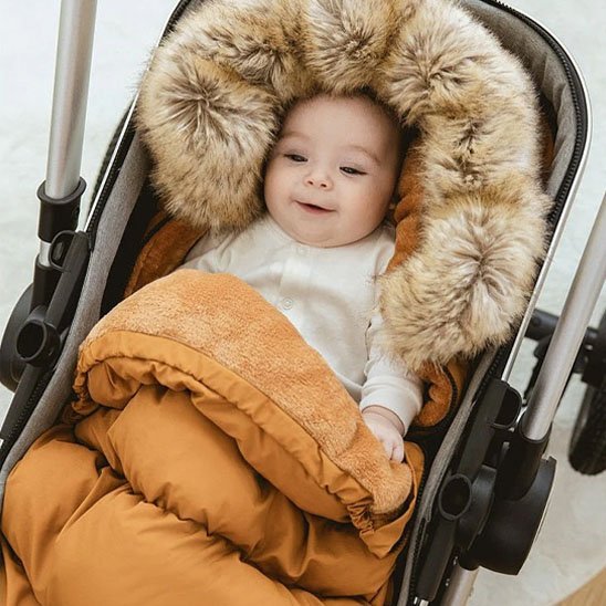 bébé souriant dans la chancelière poussette cozy universel brun