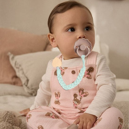 bébé assis sur le lit porte attache tetinecrochet  chou
