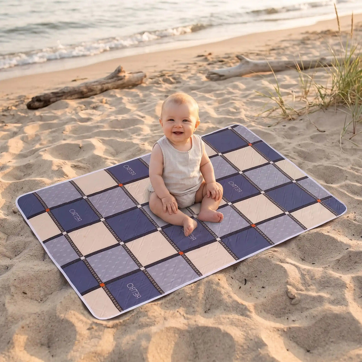 bébé assis sur tapis langer voyage carreau sur la plage