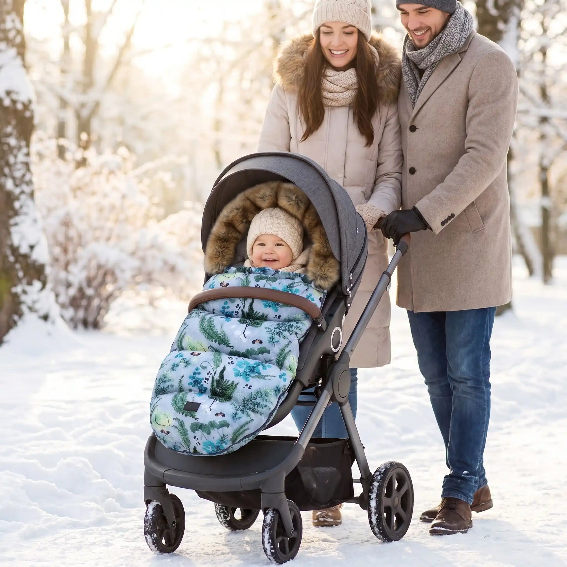 bébé dans une chanceliere chaude pour poussette babyhiver au parc avec maman et papa