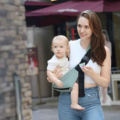 bébé dans une écharpe bebe happy avec maman devant la maison