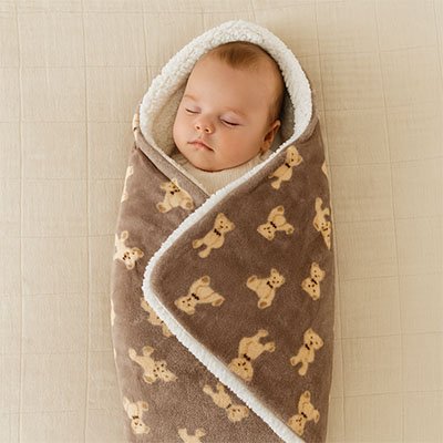 bébé endormi dans couverture poussette moelleux sur le lit