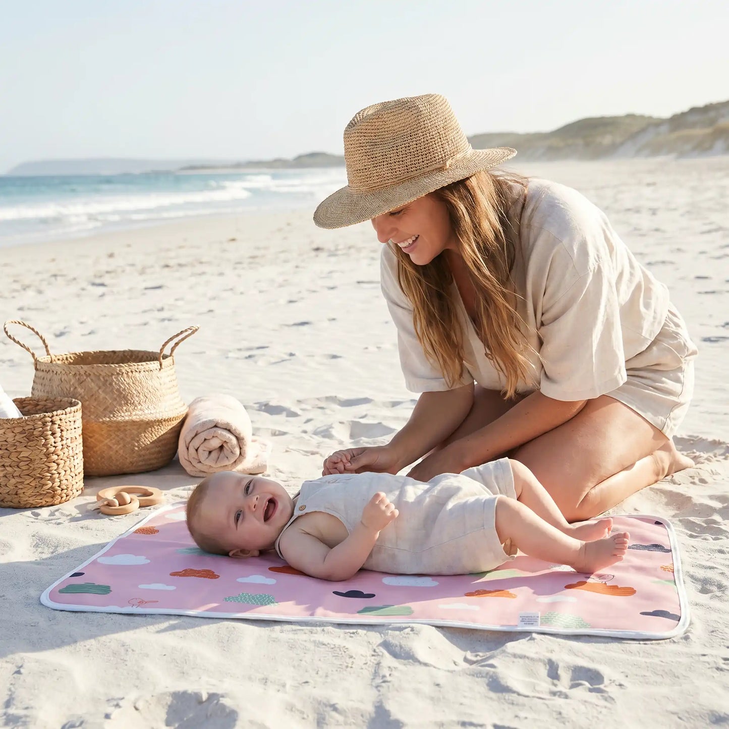 bébé sur tapis à langer respirant à la plage avec maman