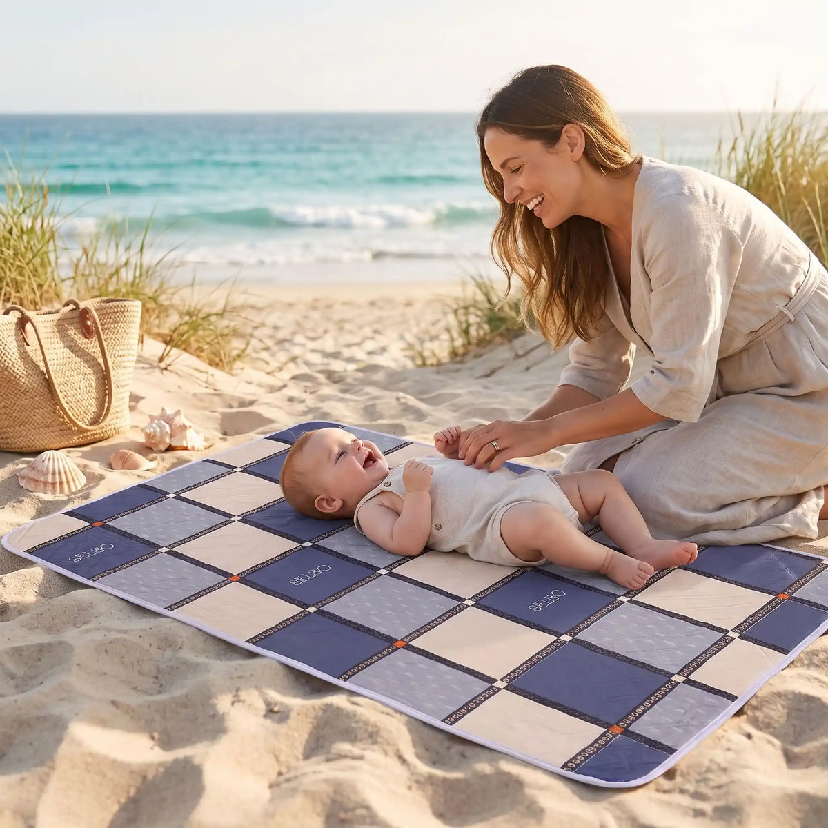 bébé sur tapis langer voyage carreau avec maman sur la plage