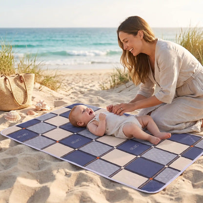 bébé sur tapis langer voyage carreau avec maman sur la plage