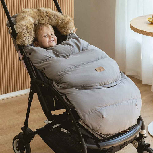 bébé souriant dans chancelière poussette cocon thermique Universel  se trouve dans le salon
