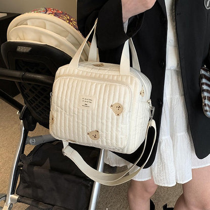 maman porte sur le bras sac a langer sport chic ourson avec la poussette
