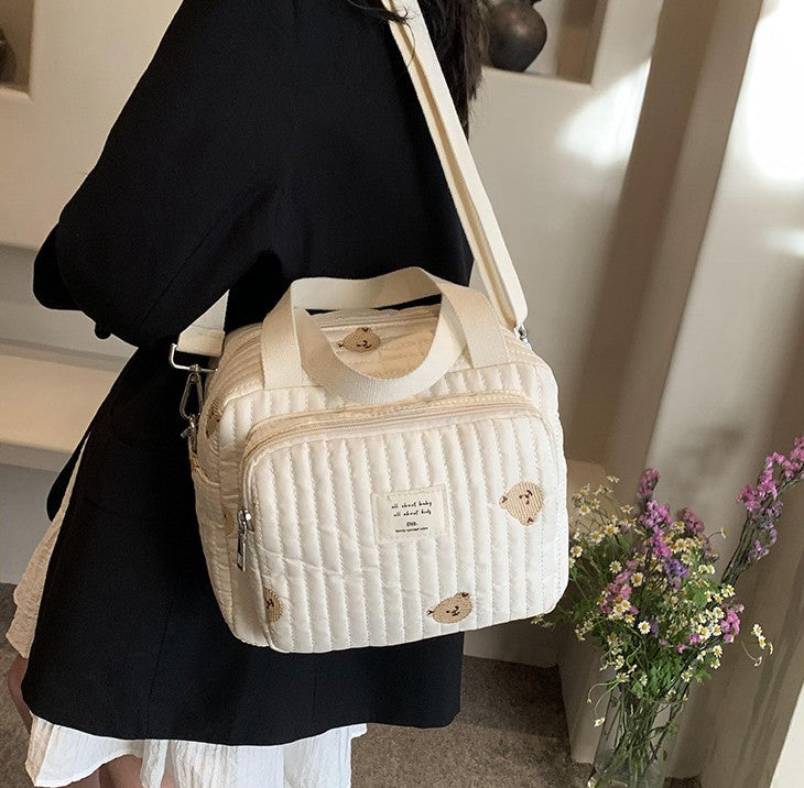 maman porte sur l'épaule sac a langer sport chic ourson dans la maison