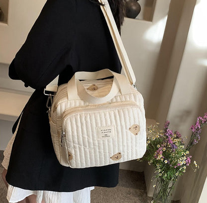 maman porte sur l'épaule sac a langer sport chic ourson dans la maison