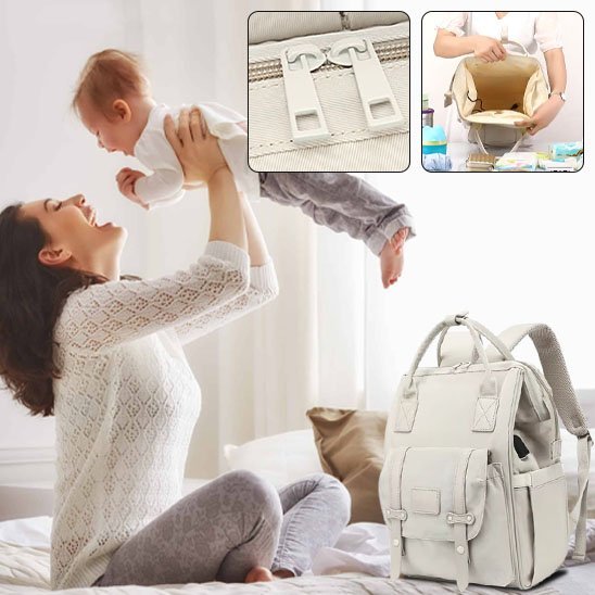 maman assise sur le lit tient bébé en l'air en souriant sac à langer momélégance à coté sur le lit