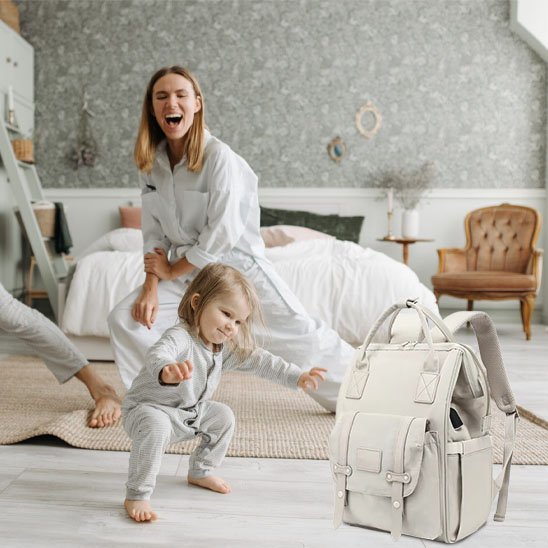 maman bébé s'amusent dans la chambre à coucher sac à langer momélégance par terre à coté d'eux
