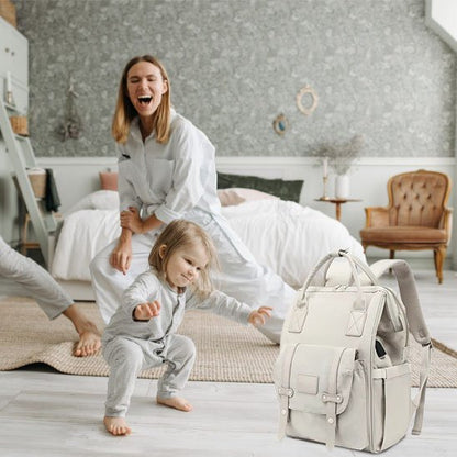 maman bébé s'amusent dans la chambre à coucher sac à langer momélégance par terre à coté d'eux