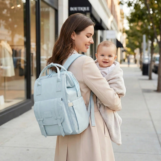 maman porte sac a dos a langer voyageur et tient bébé dans ses bras