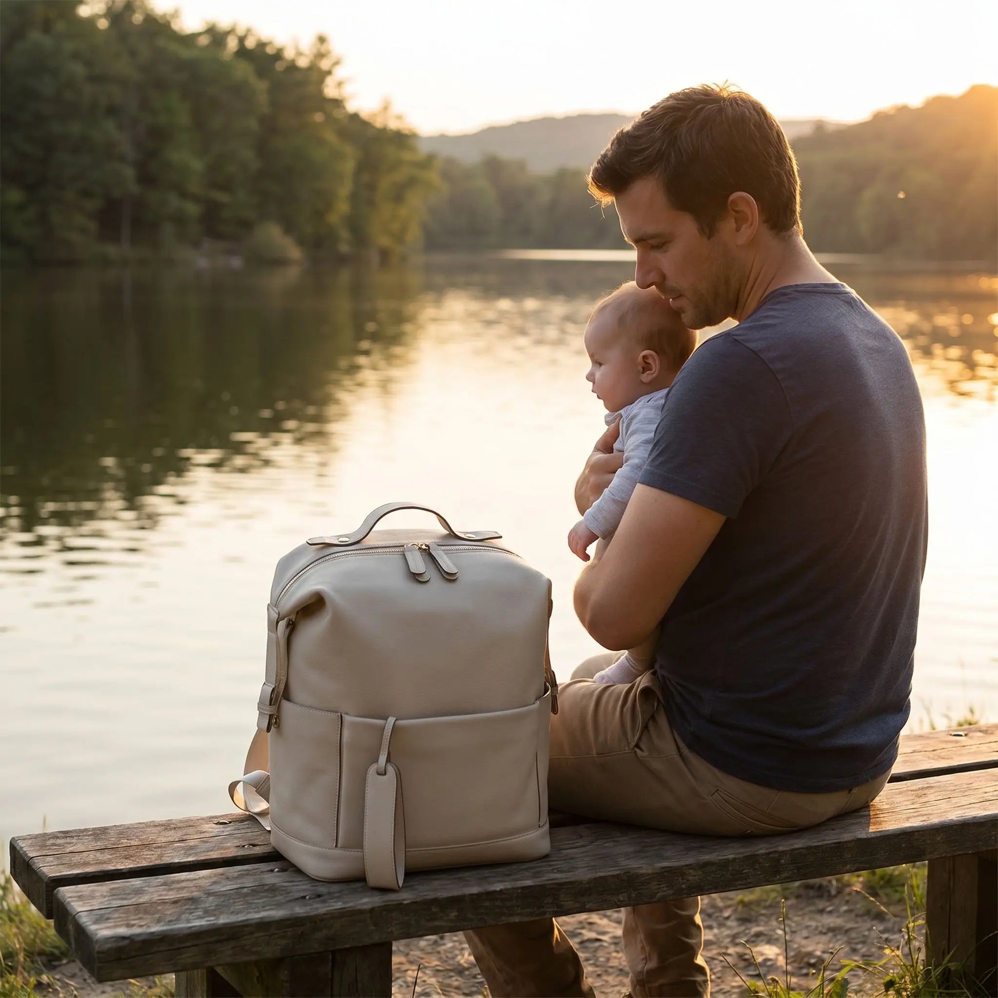 sac a dos a langer impermeable beige sur le banc au bord d'eau avec papa et bébé
